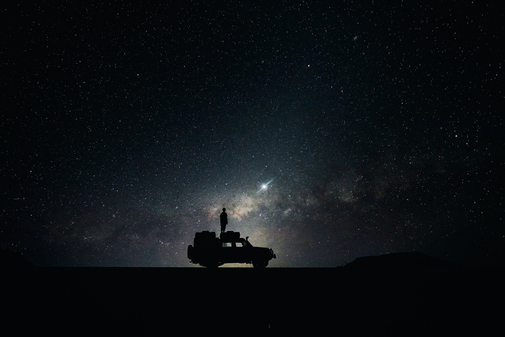 Silhouette of a Man Standing on Car at Night